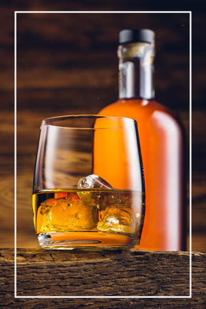 Whiskey bottle and glass on wooden table